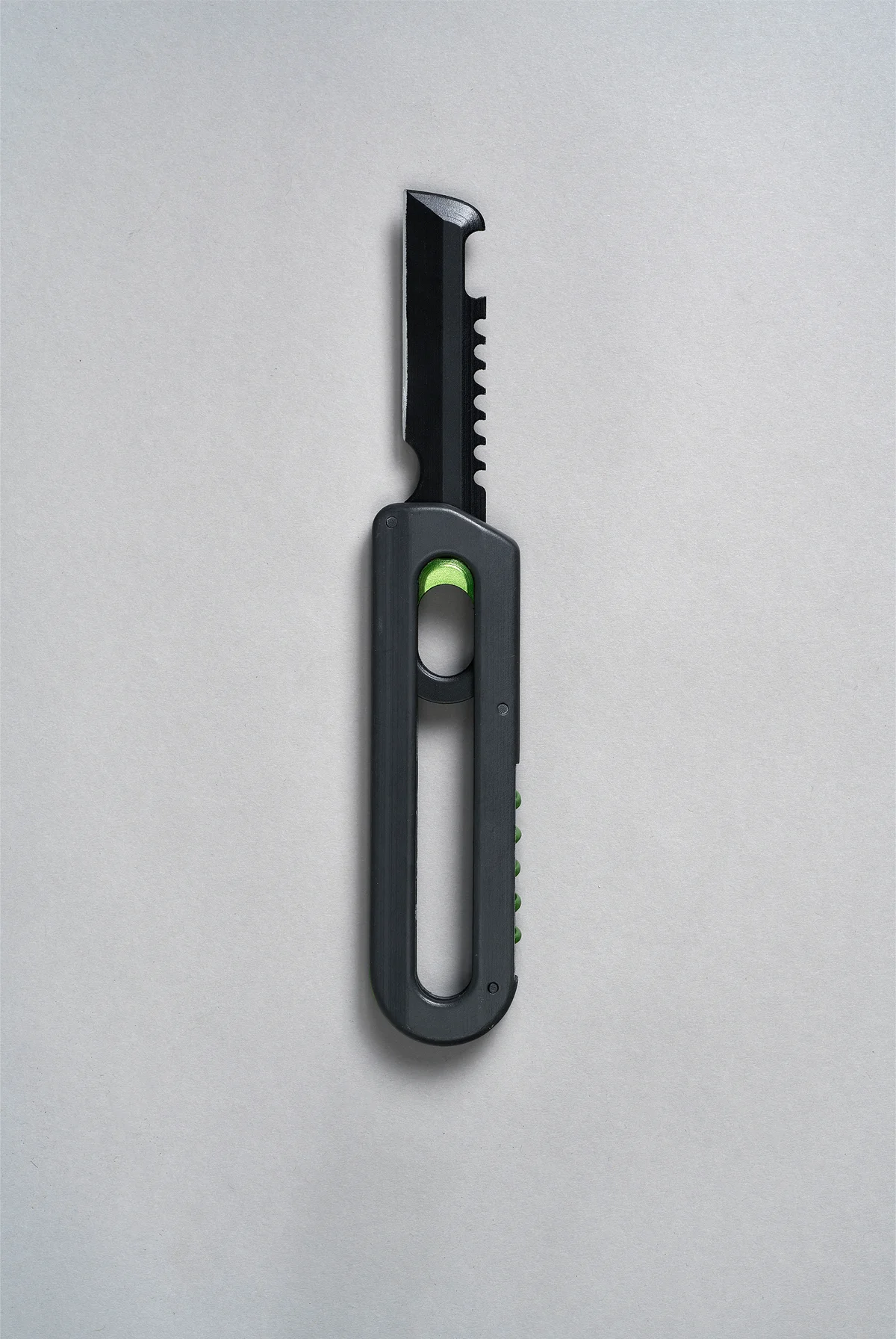 Black multi-tool with serrated blade and green slider on a grey background