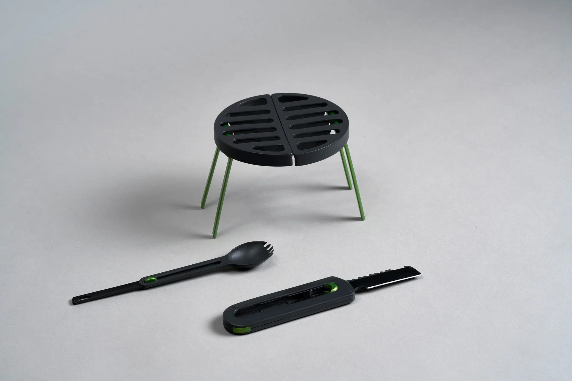 Grill, spork and multi-tool together on a grey background