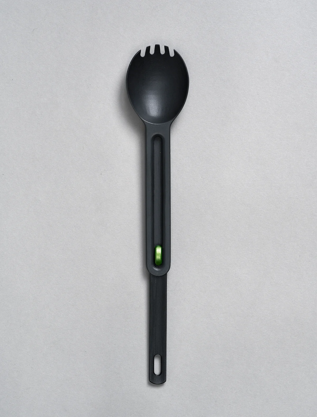 Black spork with green slider on a grey background